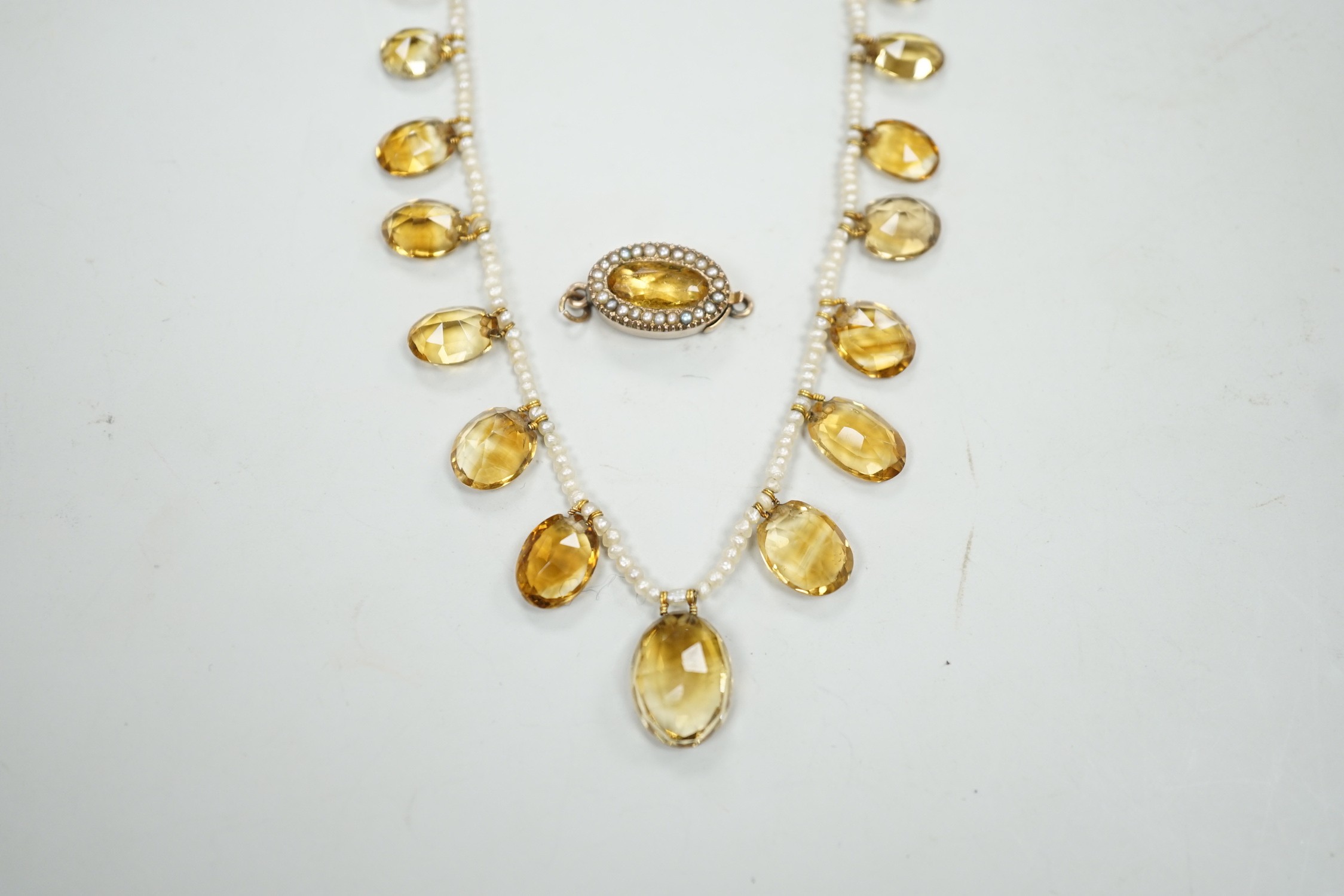 An Edwardian twenty one graduated oval cut citrine set seed pearl necklace (a.f) clasp loose, approx. 34cm.